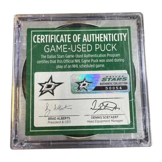A game-used hockey puck in a clear plastic protective case with a green and white Certificate of Authenticity insert. COA 