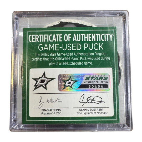 A game-used hockey puck in a clear plastic protective case with a green and white Certificate of Authenticity insert. COA 