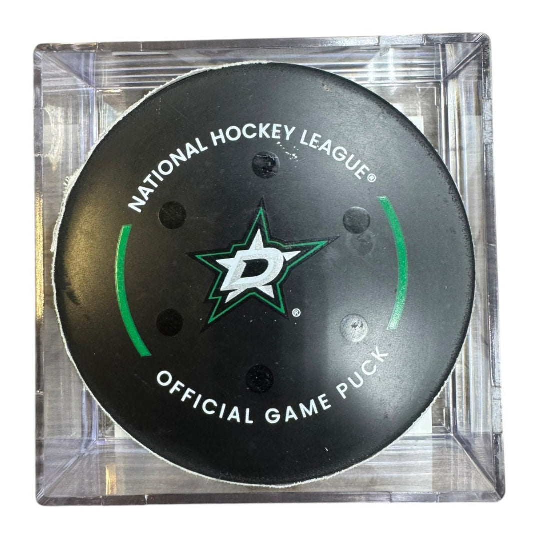 A Dallas Stars NHL official game/goal puck inside a clear plastic protective case, shown against a plain white background.
