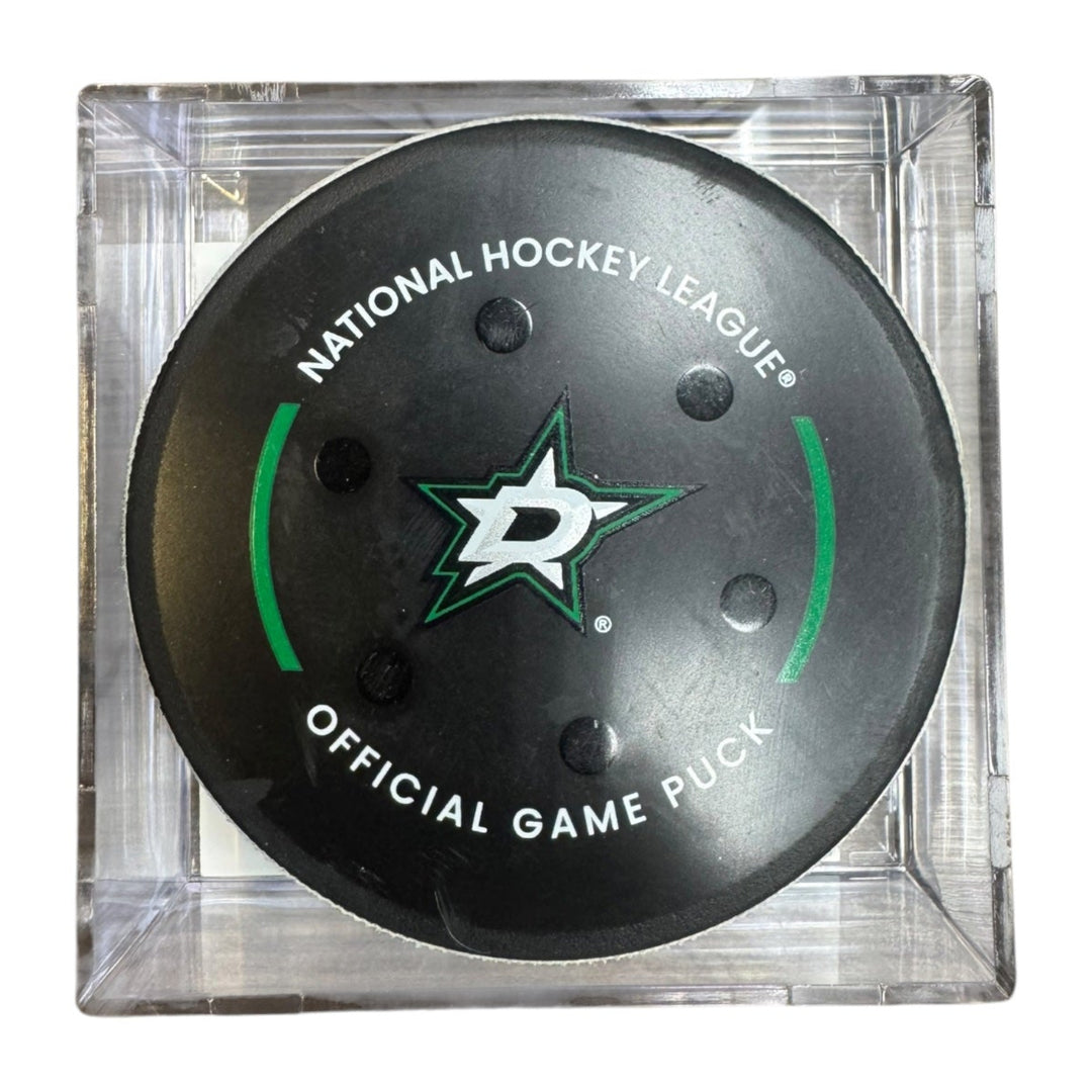 A Dallas Stars NHL official game/goal puck inside a clear plastic protective case, shown against a plain white background.
