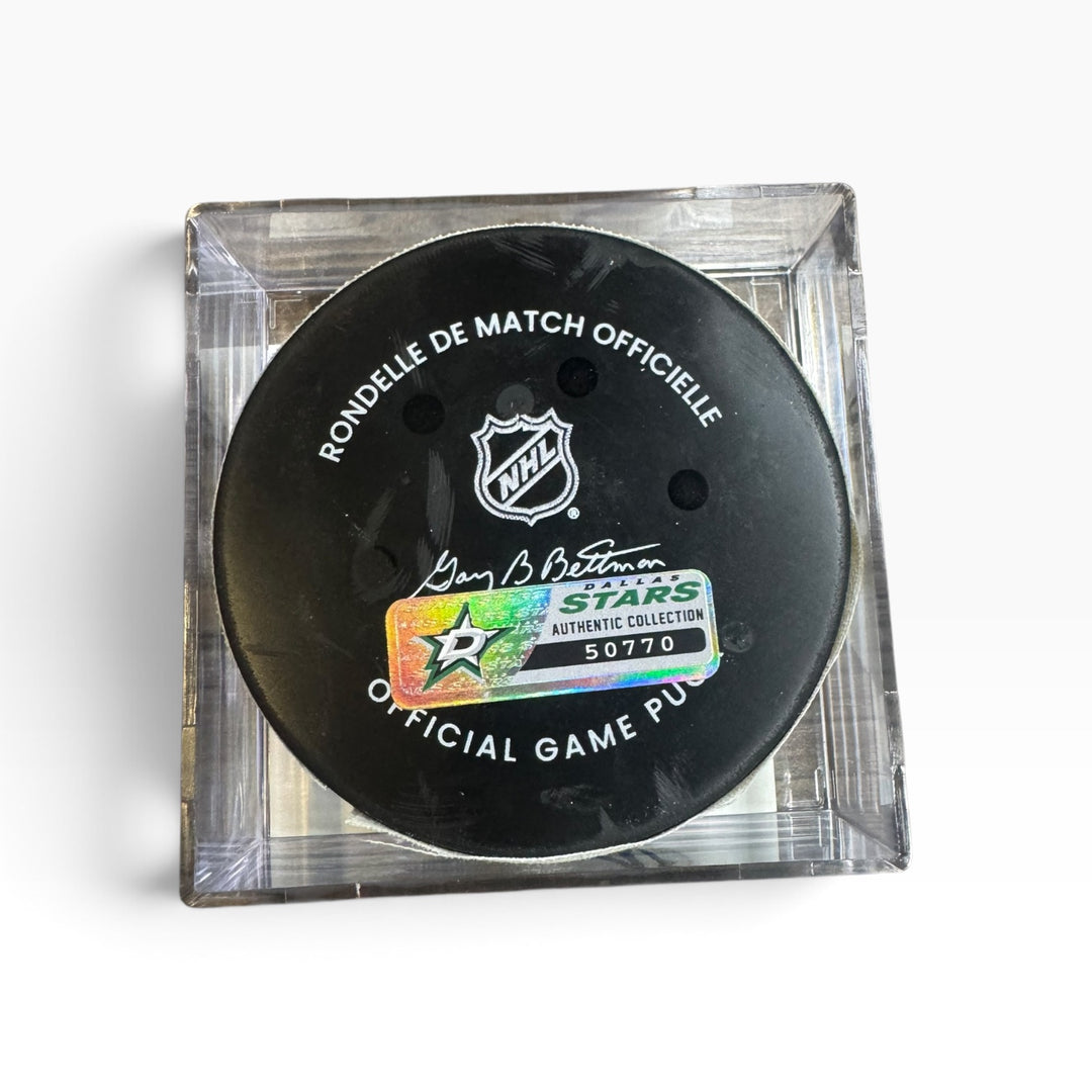 Official NHL game puck displayed inside a clear acrylic block on a white background. The puck features the NHL shield logo, a signature, and a holographic Stars Authentic Collection sticker.