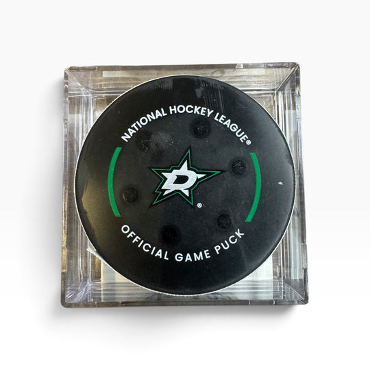 A Dallas Stars National Hockey League official game puck in a clear square plastic display case, photographed from directly above on a white background.