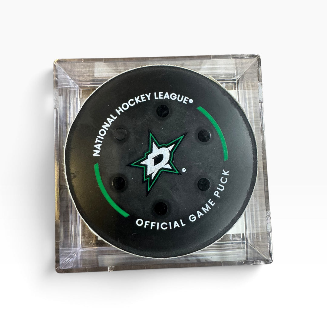 Dallas Stars National Hockey League official game puck in a clear square plastic case, photographed from above on a white background.