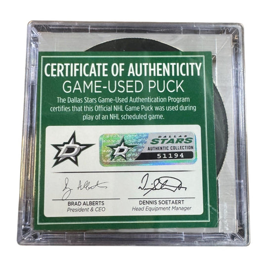 A game-used hockey puck in a clear plastic protective case with a green and white Certificate of Authenticity insert. COA 