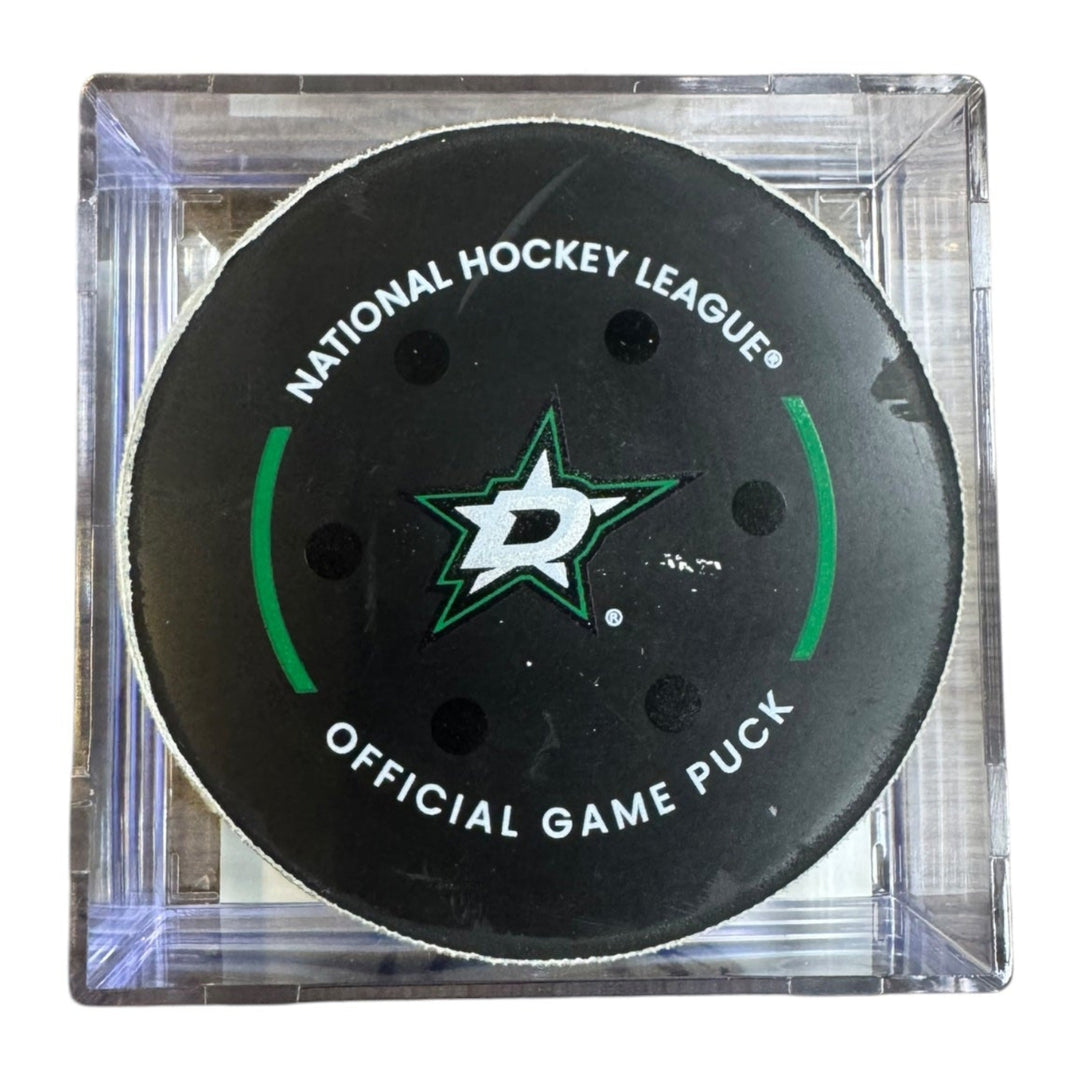 A Dallas Stars NHL official game/goal puck inside a clear plastic protective case, shown against a plain white background.
