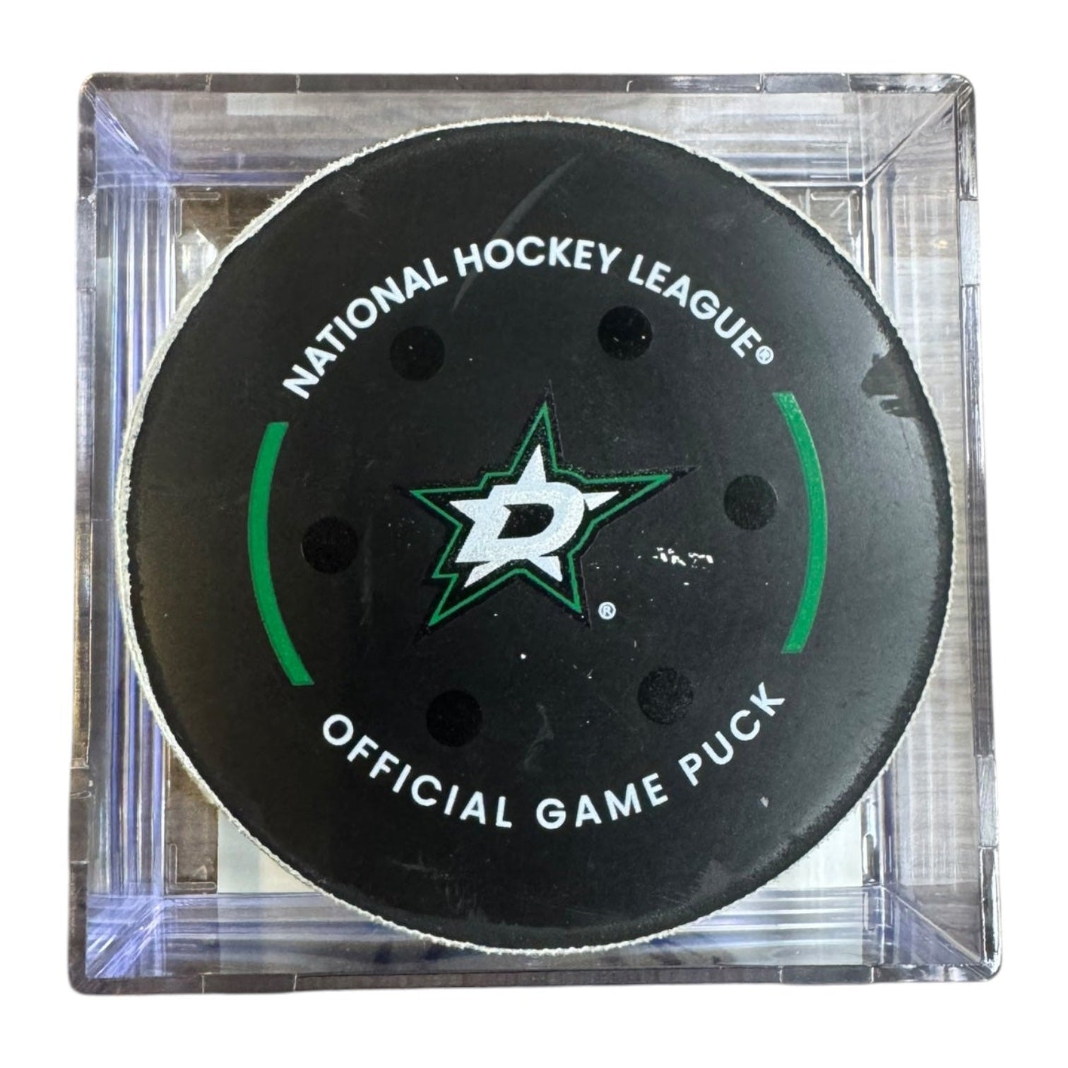 A Dallas Stars NHL official game/goal puck inside a clear plastic protective case, shown against a plain white background.
