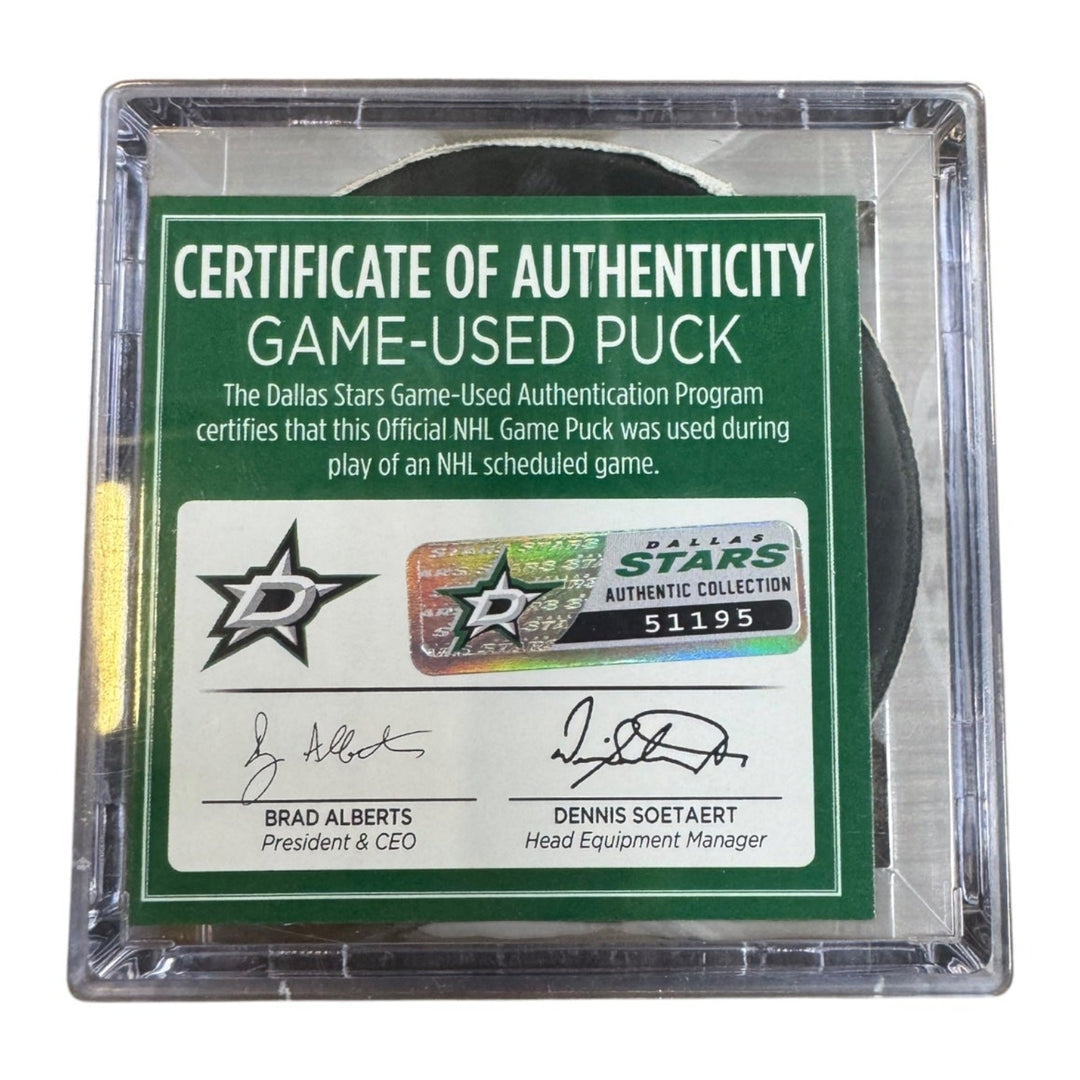 A game-used hockey puck in a clear plastic protective case with a green and white Certificate of Authenticity insert. COA 