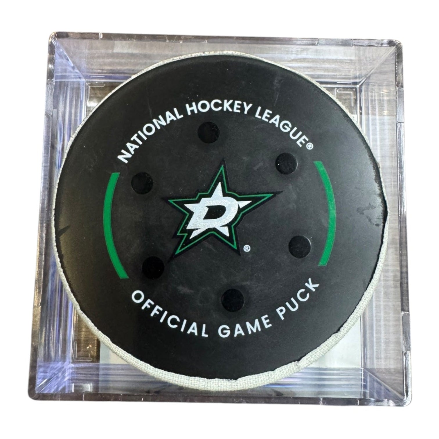 A Dallas Stars NHL official game/goal puck inside a clear plastic protective case, shown against a plain white background.
