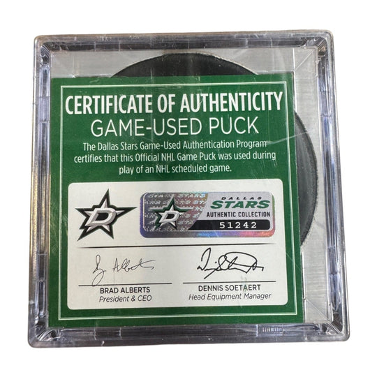 A game-used hockey puck in a clear plastic protective case with a green and white Certificate of Authenticity insert. COA 