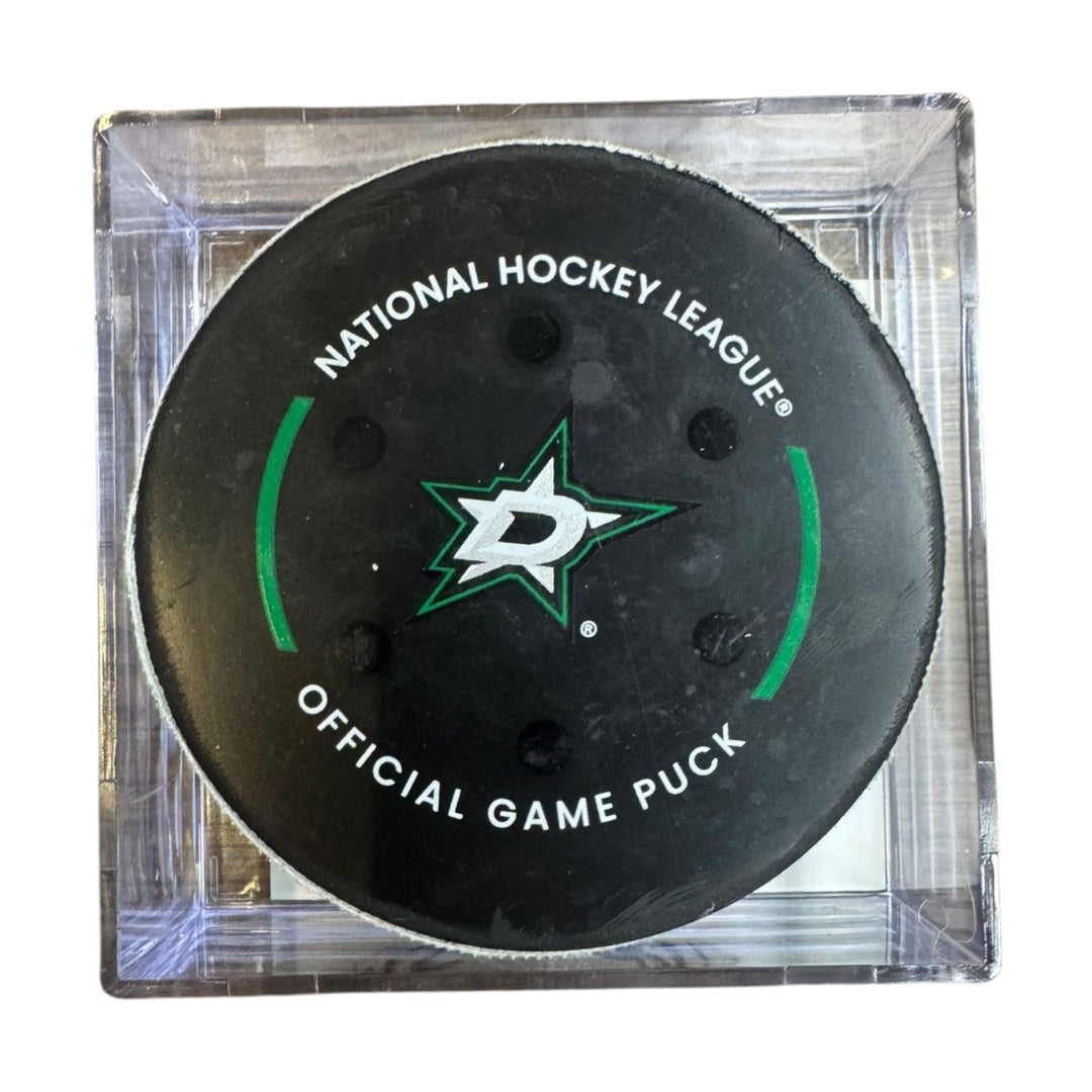 A Dallas Stars NHL official game/goal puck inside a clear plastic protective case, shown against a plain white background.
