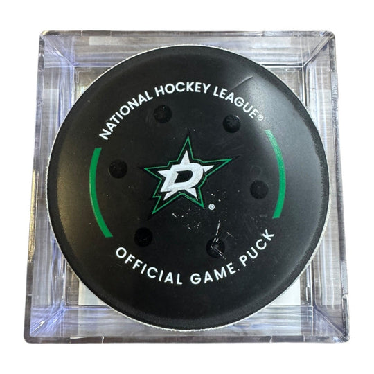 A Dallas Stars NHL official game/goal puck inside a clear plastic protective case, shown against a plain white background.
