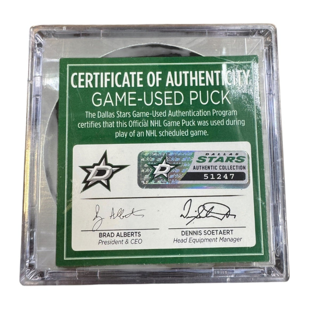 A game-used hockey puck in a clear plastic protective case with a green and white Certificate of Authenticity insert. COA 