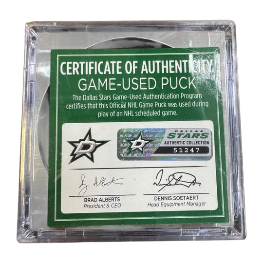 A game-used hockey puck in a clear plastic protective case with a green and white Certificate of Authenticity insert. COA 