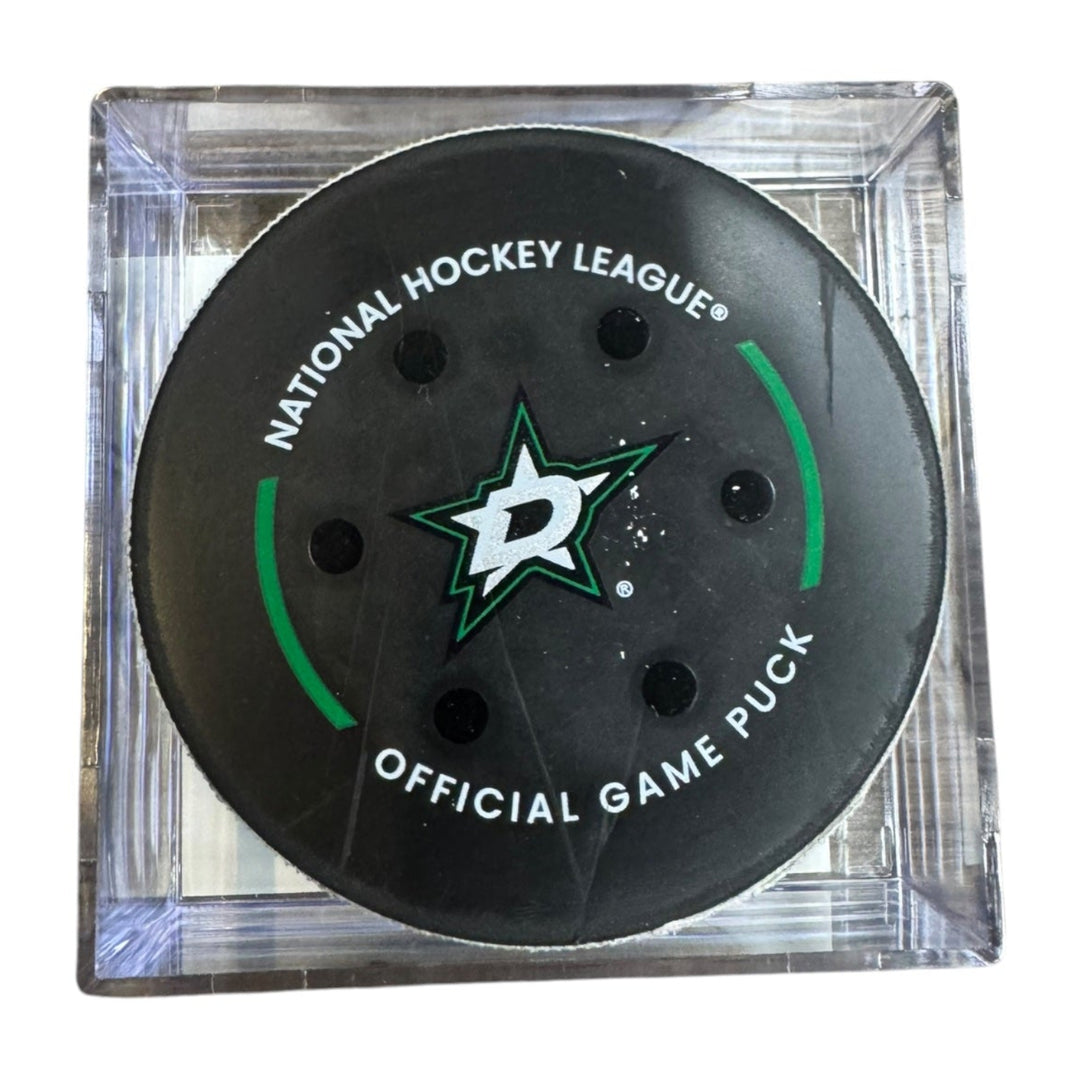 A Dallas Stars NHL official game/goal puck inside a clear plastic protective case, shown against a plain white background.
