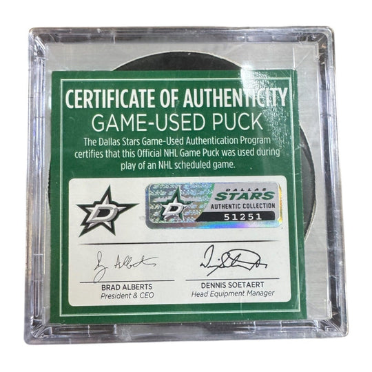 A game-used hockey puck in a clear plastic protective case with a green and white Certificate of Authenticity insert. COA 
