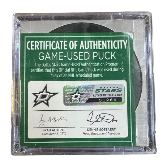 A game-used hockey puck in a clear plastic protective case with a green and white Certificate of Authenticity insert. COA 