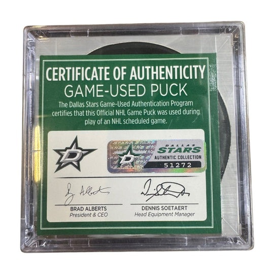 A game-used hockey puck in a clear plastic protective case with a green and white Certificate of Authenticity insert. COA 