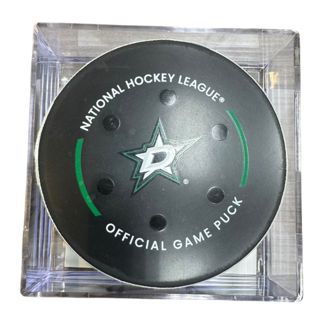 A Dallas Stars NHL official game/goal puck inside a clear plastic protective case, shown against a plain white background.
