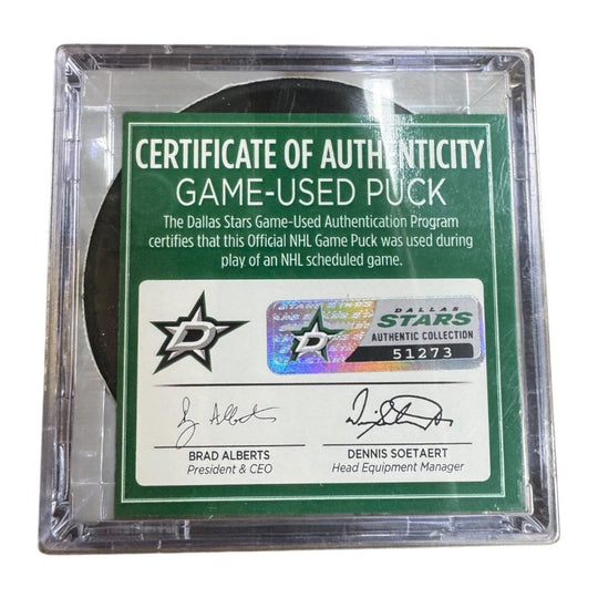A game-used hockey puck in a clear plastic protective case with a green and white Certificate of Authenticity insert. COA 