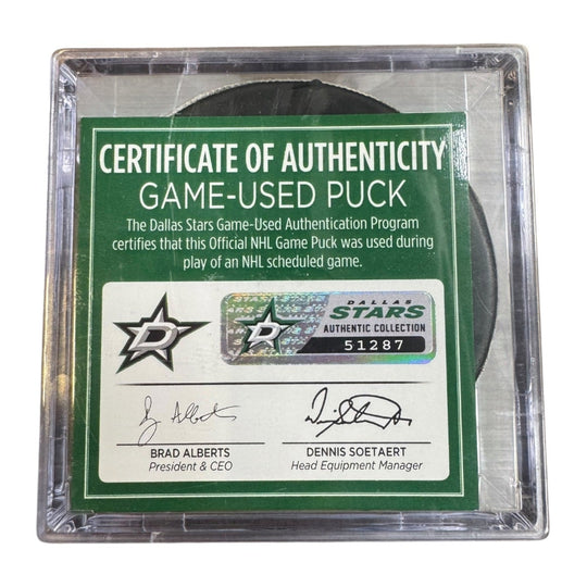 A game-used hockey puck in a clear plastic protective case with a green and white Certificate of Authenticity insert. COA 