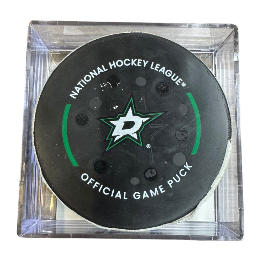 A Dallas Stars NHL official game/goal puck inside a clear plastic protective case, shown against a plain white background.

