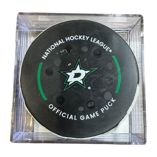 A Dallas Stars NHL official game/goal puck inside a clear plastic protective case, shown against a plain white background.

