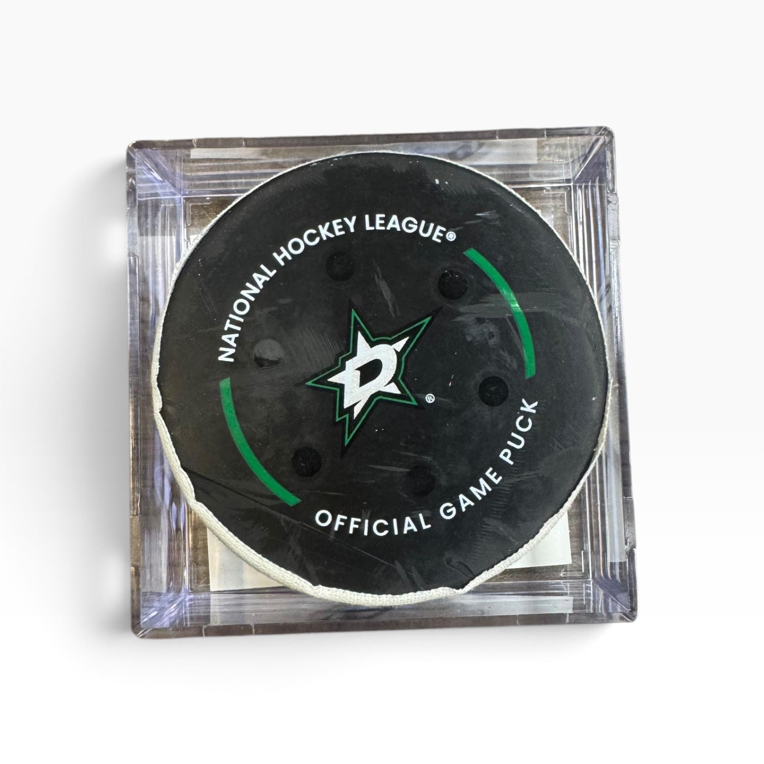 A Dallas Stars National Hockey League official game puck in a clear square acrylic holder, shown on a white background.