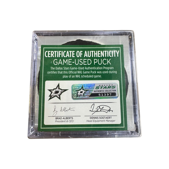A game-used hockey puck in a clear plastic protective case with a green and white Certificate of Authenticity insert. COA 