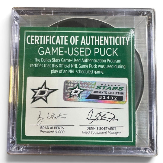 A game-used hockey puck in a clear plastic protective case with a green and white Certificate of Authenticity insert. COA 