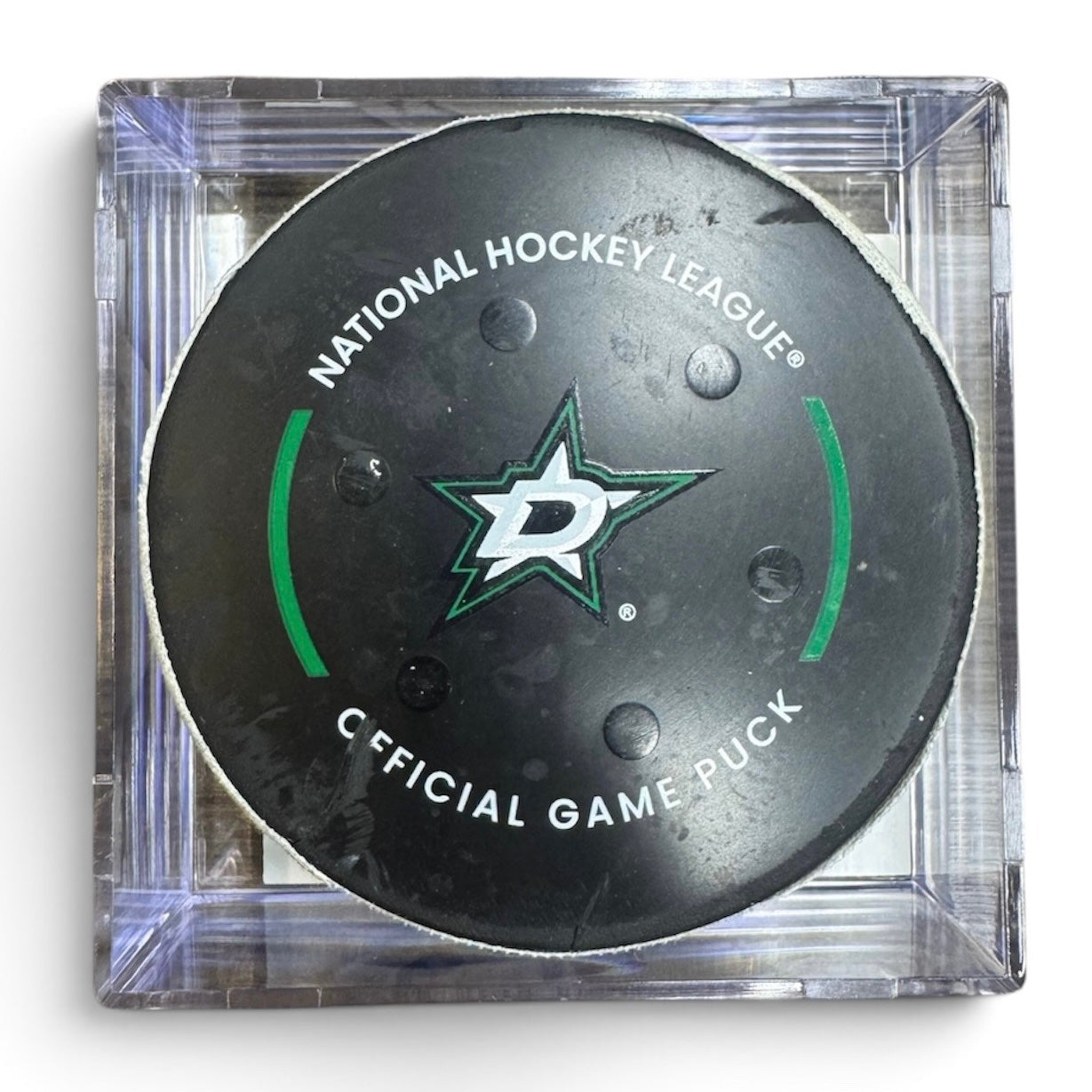 A Dallas Stars NHL official game/goal puck inside a clear plastic protective case, shown against a plain white background.