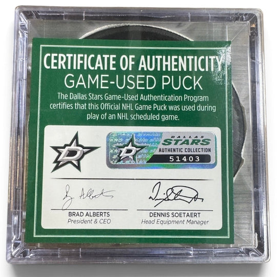 A game-used hockey puck in a clear plastic protective case with a green and white Certificate of Authenticity insert. COA 
