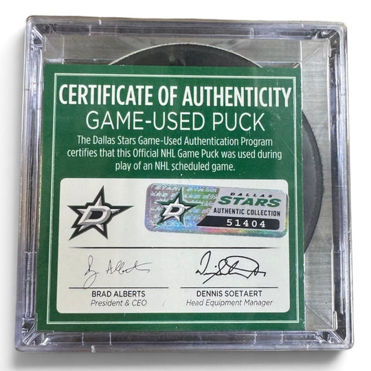 A game-used hockey puck in a clear plastic protective case with a green and white Certificate of Authenticity insert. COA 