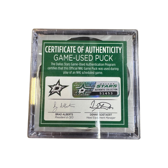 A game-used hockey puck in a clear plastic protective case with a green and white Certificate of Authenticity insert. COA 