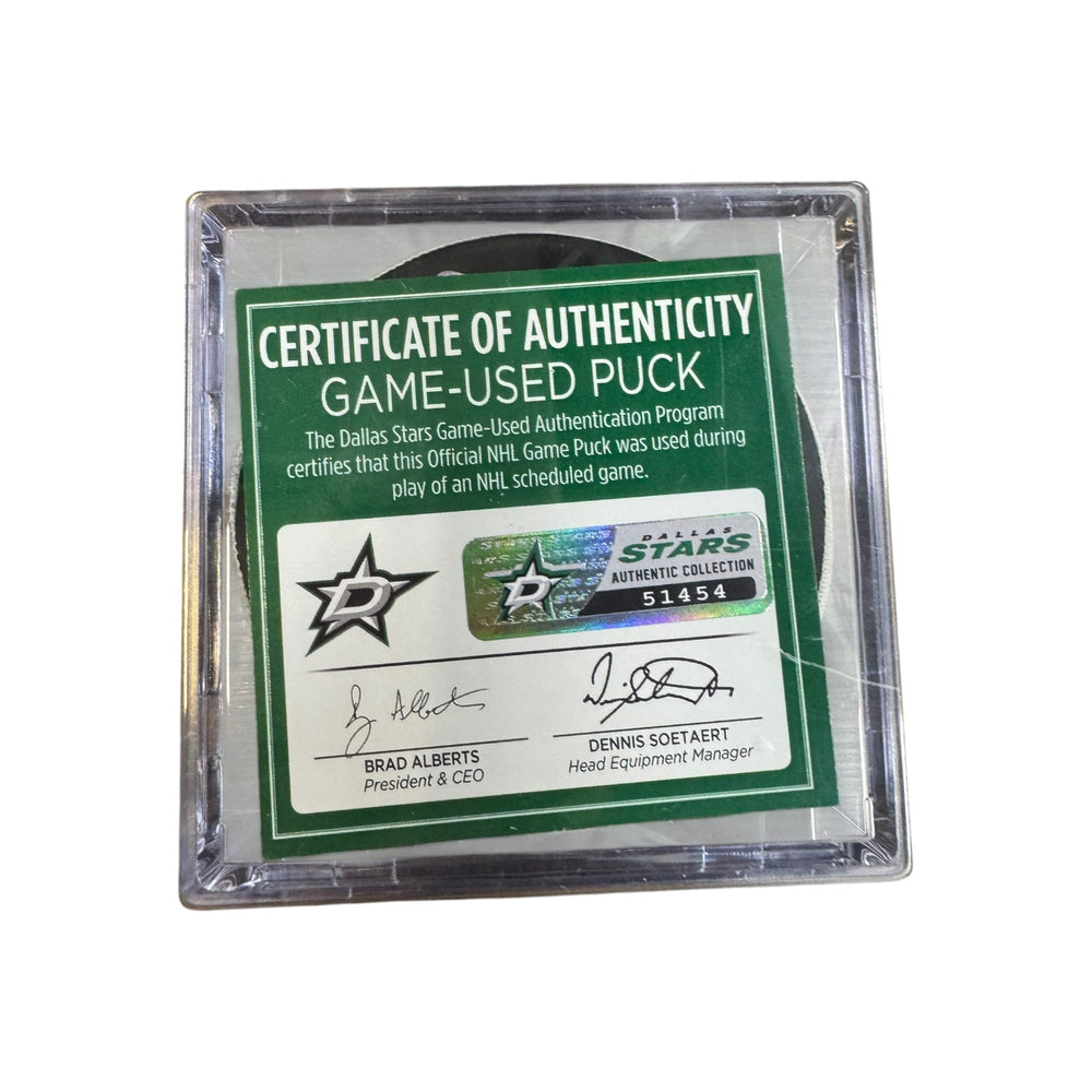 A game-used hockey puck in a clear plastic protective case with a green and white Certificate of Authenticity insert. COA #  51454