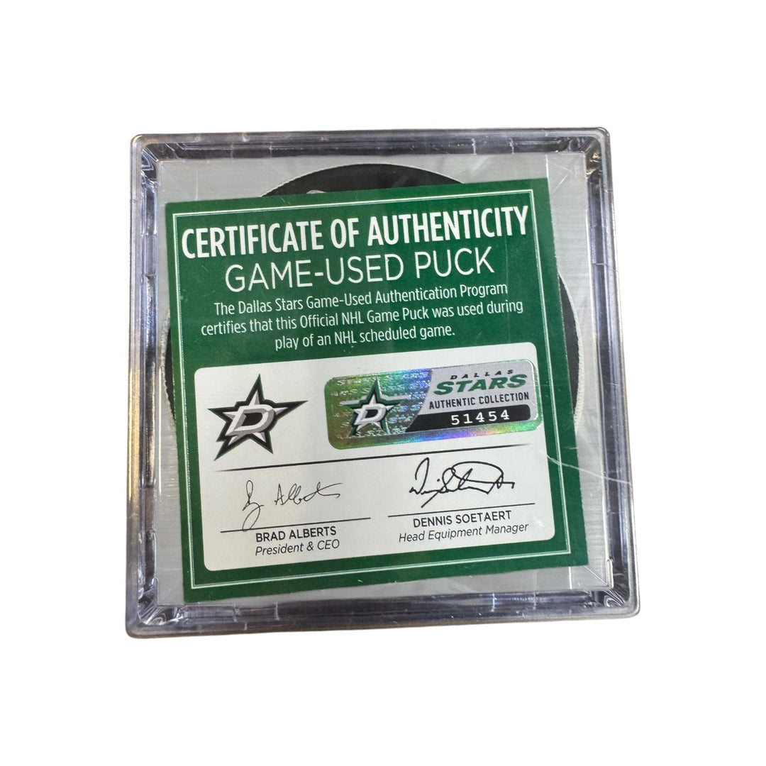 A game-used hockey puck in a clear plastic protective case with a green and white Certificate of Authenticity insert. COA 