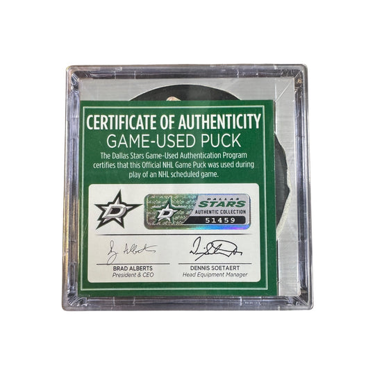A game-used hockey puck in a clear plastic protective case with a green and white Certificate of Authenticity insert. COA 