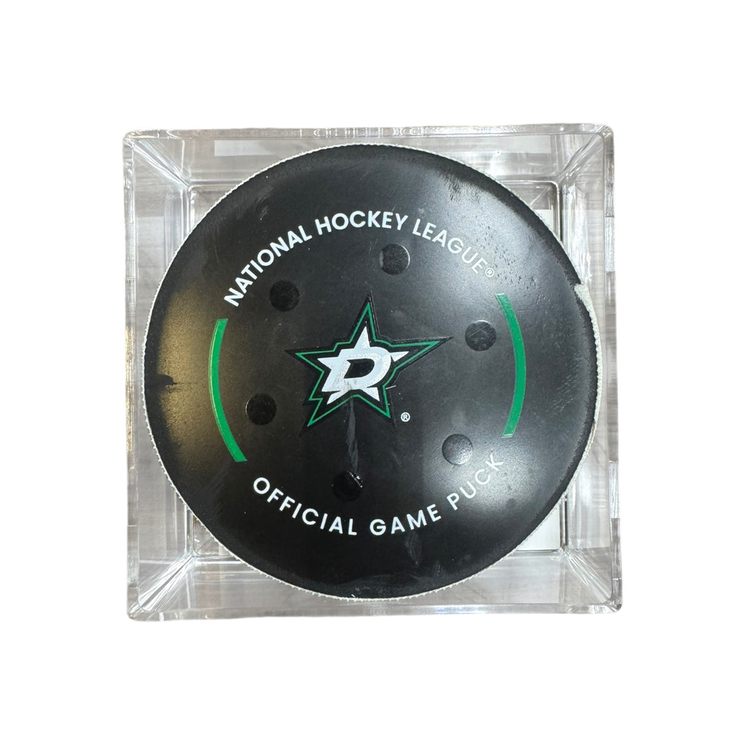 A Dallas Stars NHL official game/goal puck inside a clear plastic protective case, shown against a plain white background.
