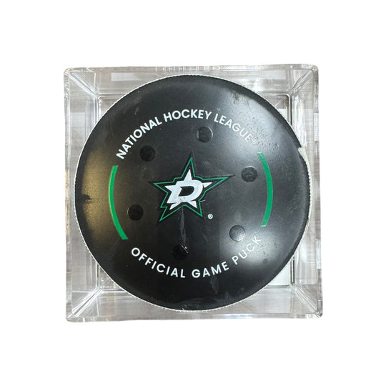A Dallas Stars NHL official game/goal puck inside a clear plastic protective case, shown against a plain white background.
