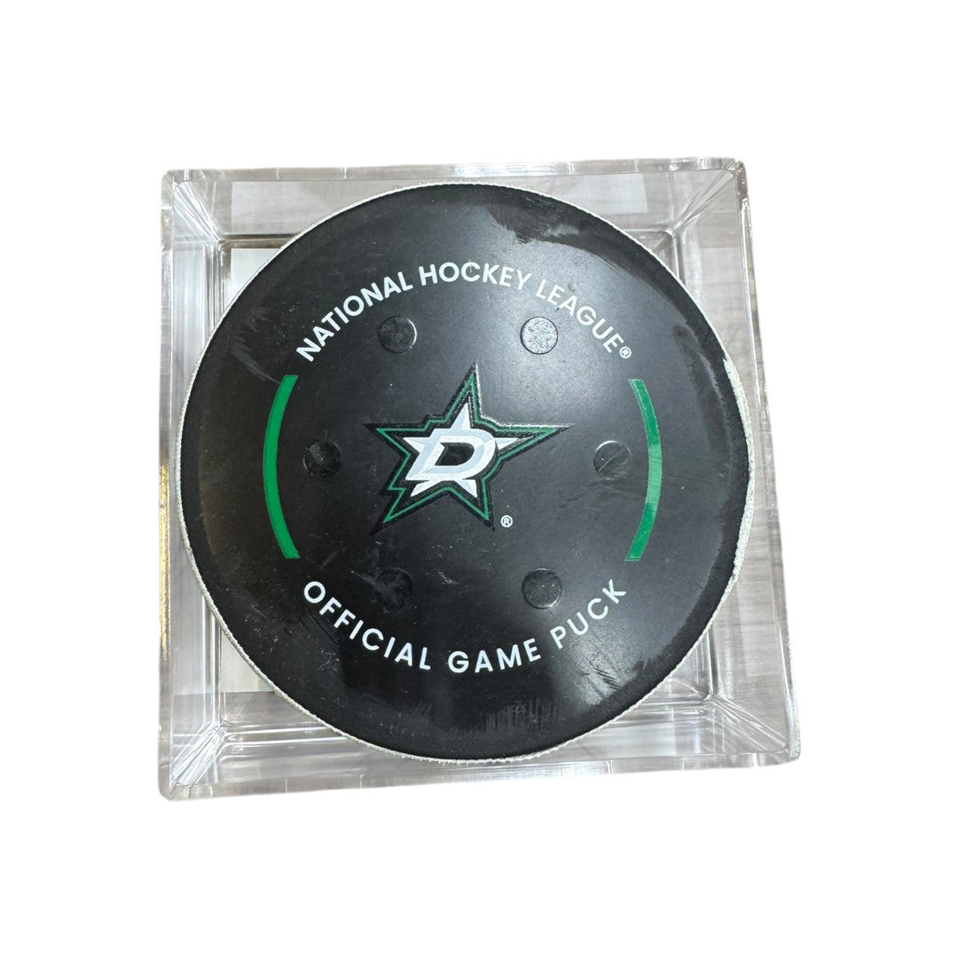 A Dallas Stars NHL official game/goal puck inside a clear plastic protective case, shown against a plain white background.
