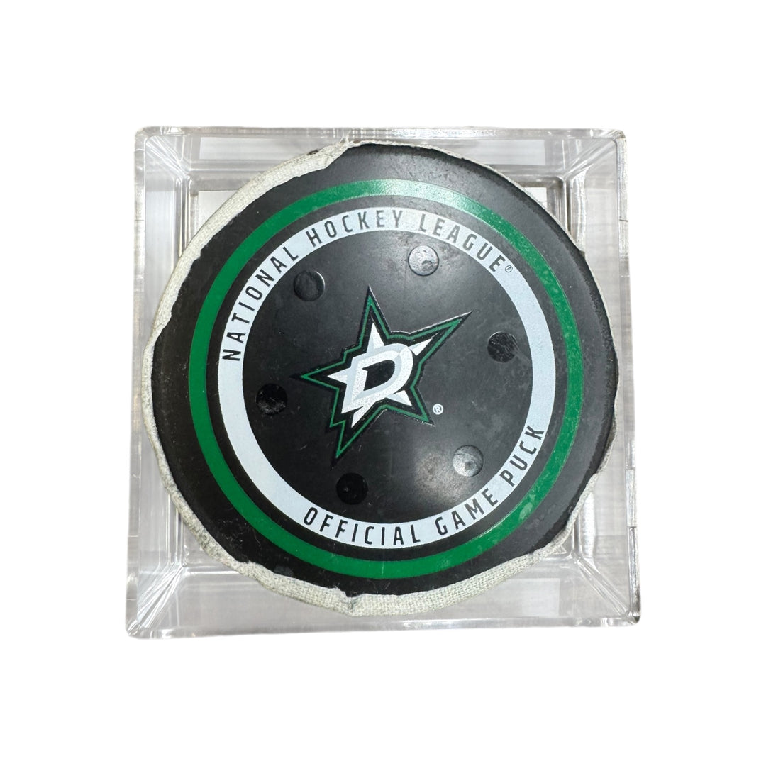 A Dallas Stars NHL official game/goal puck inside a clear plastic protective case, shown against a plain white background.
