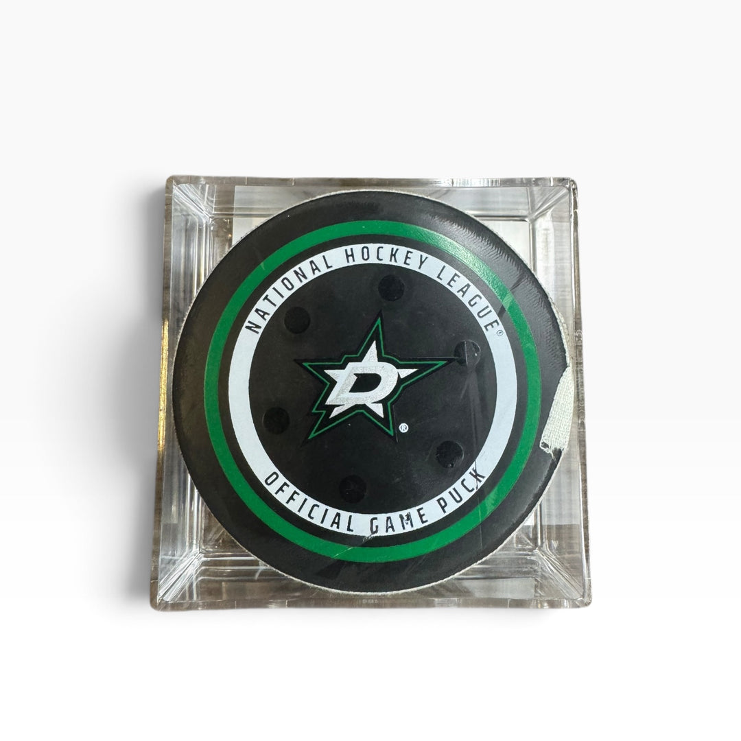 Dallas Stars official playoff hockey game puck displayed inside a clear square acrylic case on a white background.
