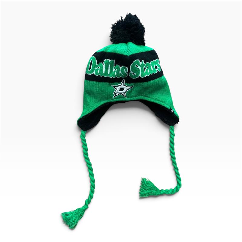 A green and black Dallas Stars knit pom-pom beanie hat with ear flaps and braided drawstrings, shown on a plain white background.