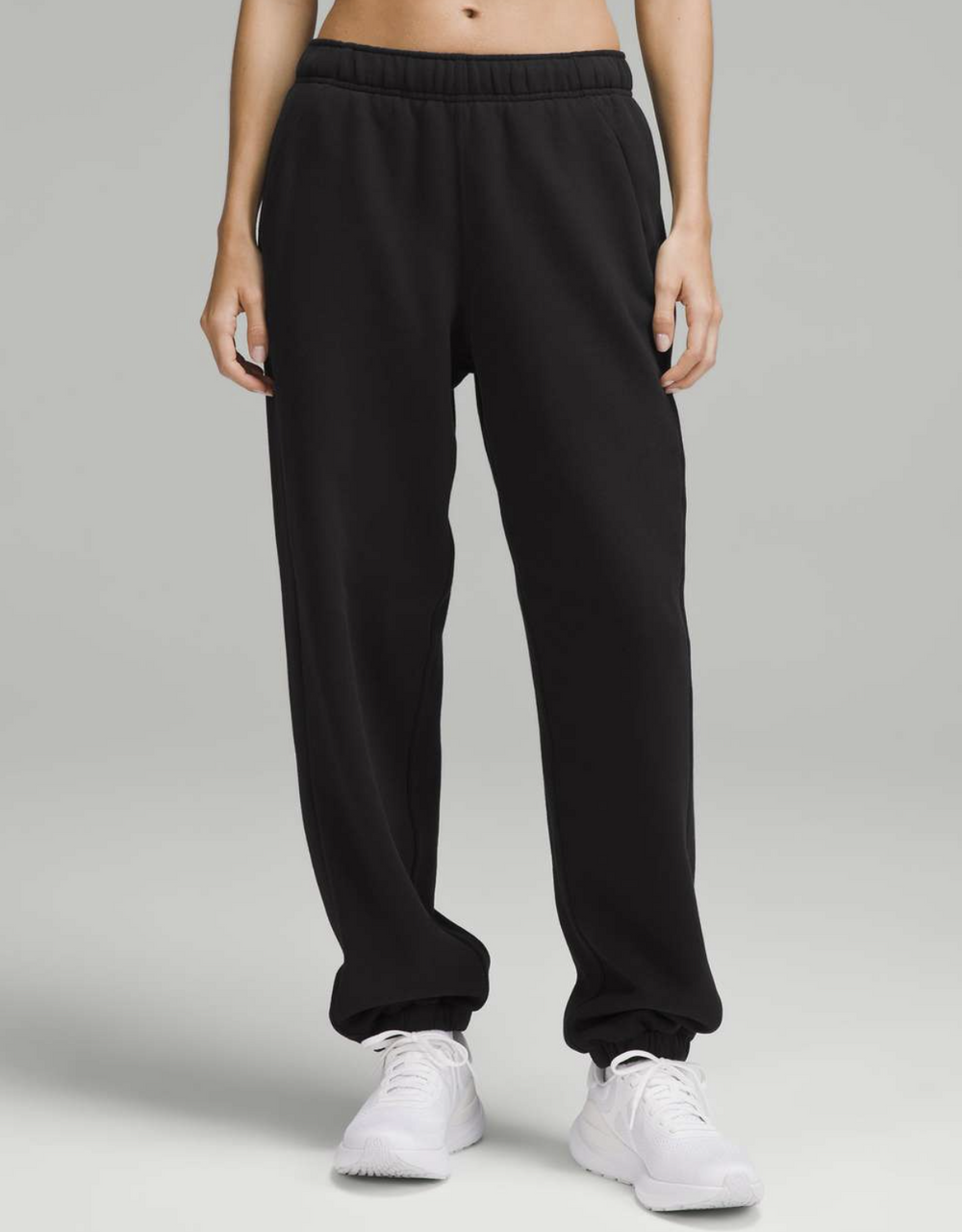 Person wearing black sweatpants on a gray background