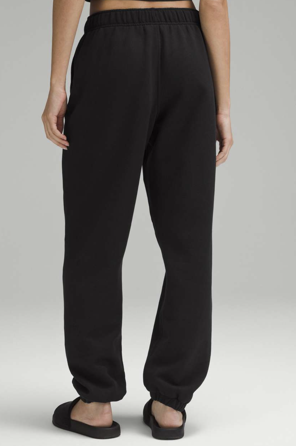 Black sweatpants worn by a person on a plain background